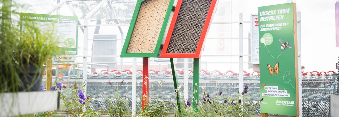 Zwei Insektenhotels vor einem Beet